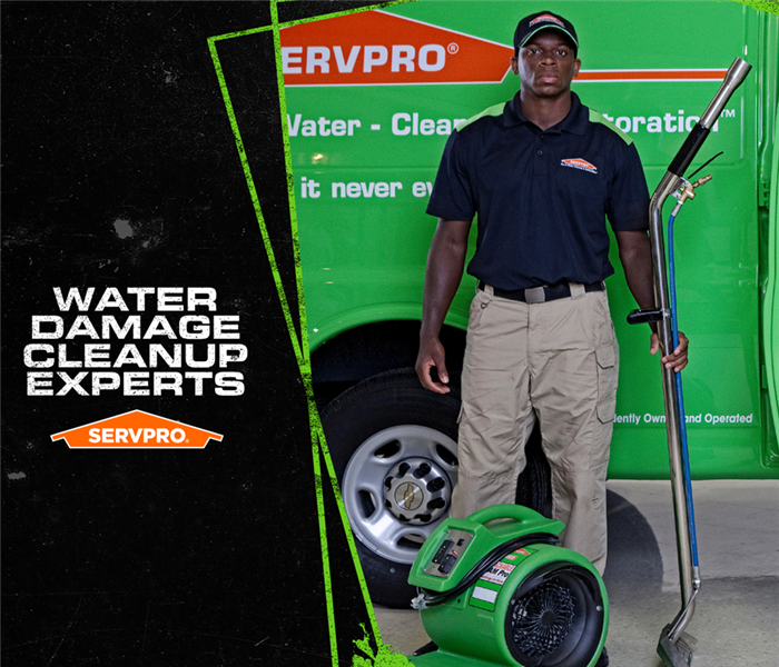 SERVPRO employee standing in front of a SERVPRO van holding a water extraction tool